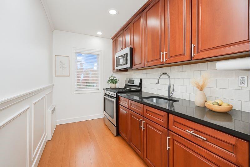 248 Bay 19th Street, Unit B Brooklyn, NY 11214 - Photo 8 of 14 a kitchen with granite countertop wooden cabinets stainless steel appliances and a sink