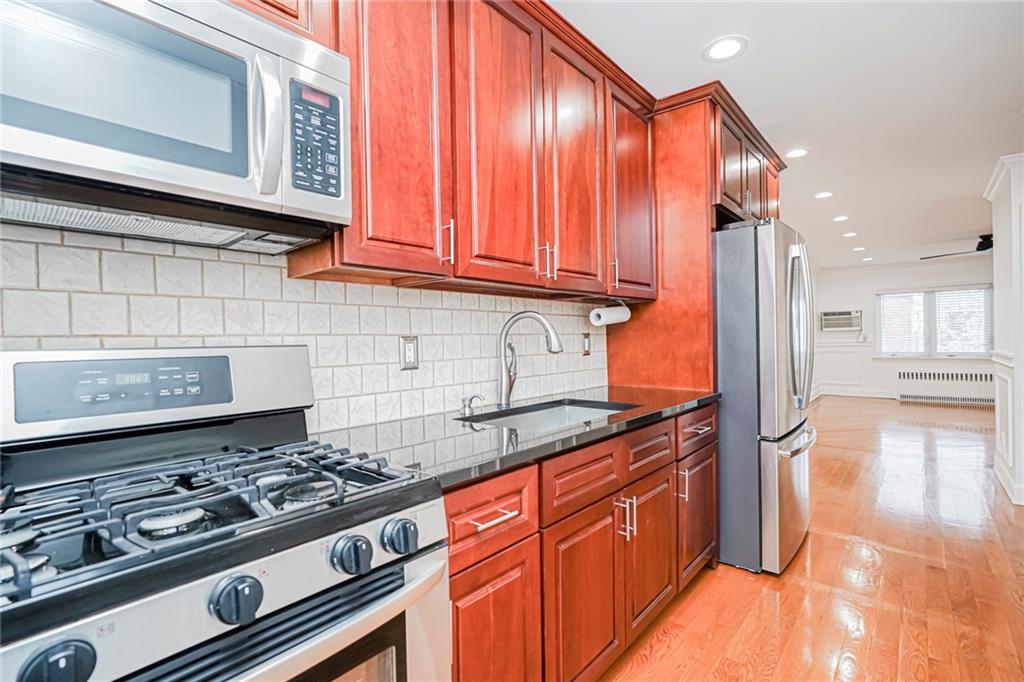 248 Bay 19th Street, Unit B Brooklyn, NY 11214 - Photo 10 of 14 a kitchen with stainless steel appliances granite countertop a stove and a wooden cabinets