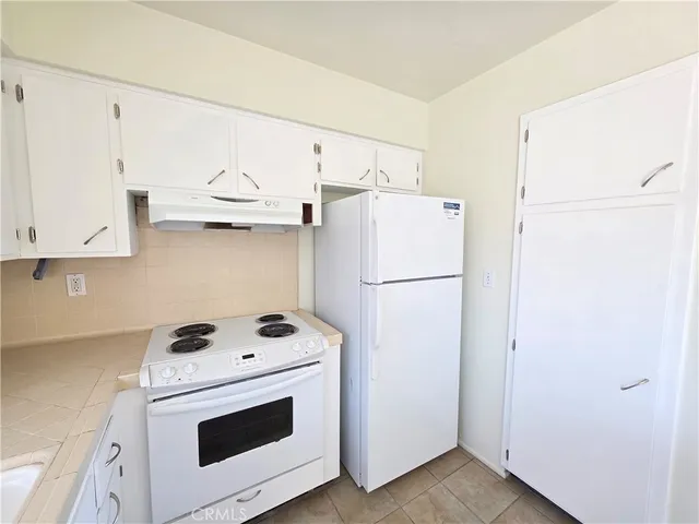 a kitchen with refrigerator a stove a microwave and white cabinets