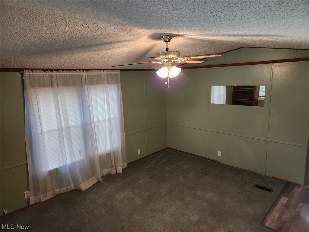 3895 Middletown Road East Youngstown, OH 44514 - Photo 10 of 28 Empty room with dark carpet, lofted ceiling, ceiling fan, and a textured ceiling