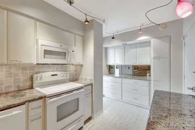 a kitchen with white cabinets and refrigerator