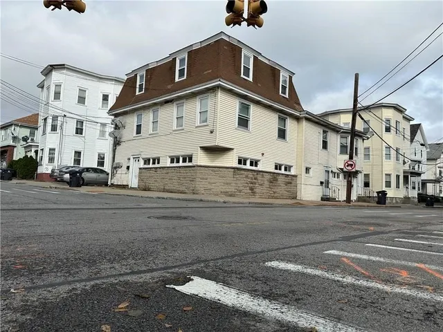 a view of a white building among the street with parked cars