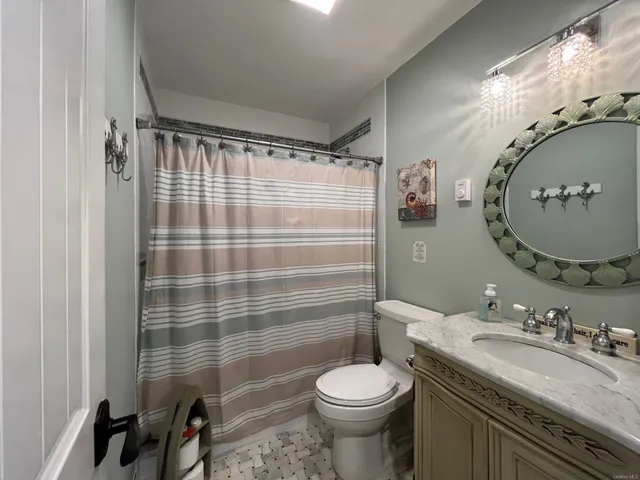 a bathroom with a granite countertop sink toilet a mirror and shower curtain