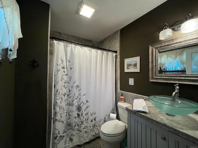 a bathroom with a granite countertop toilet sink and mirror