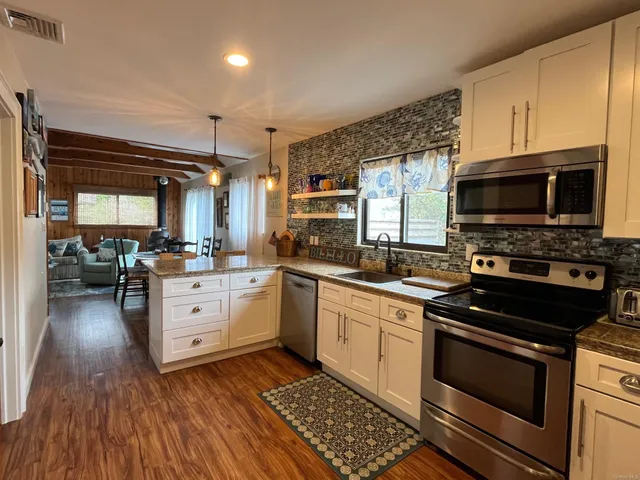 a kitchen with stainless steel appliances a stove a sink a microwave a stove and white cabinets