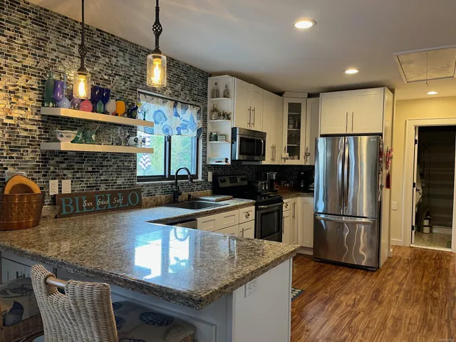 a kitchen with stainless steel appliances granite countertop a sink a stove and a refrigerator