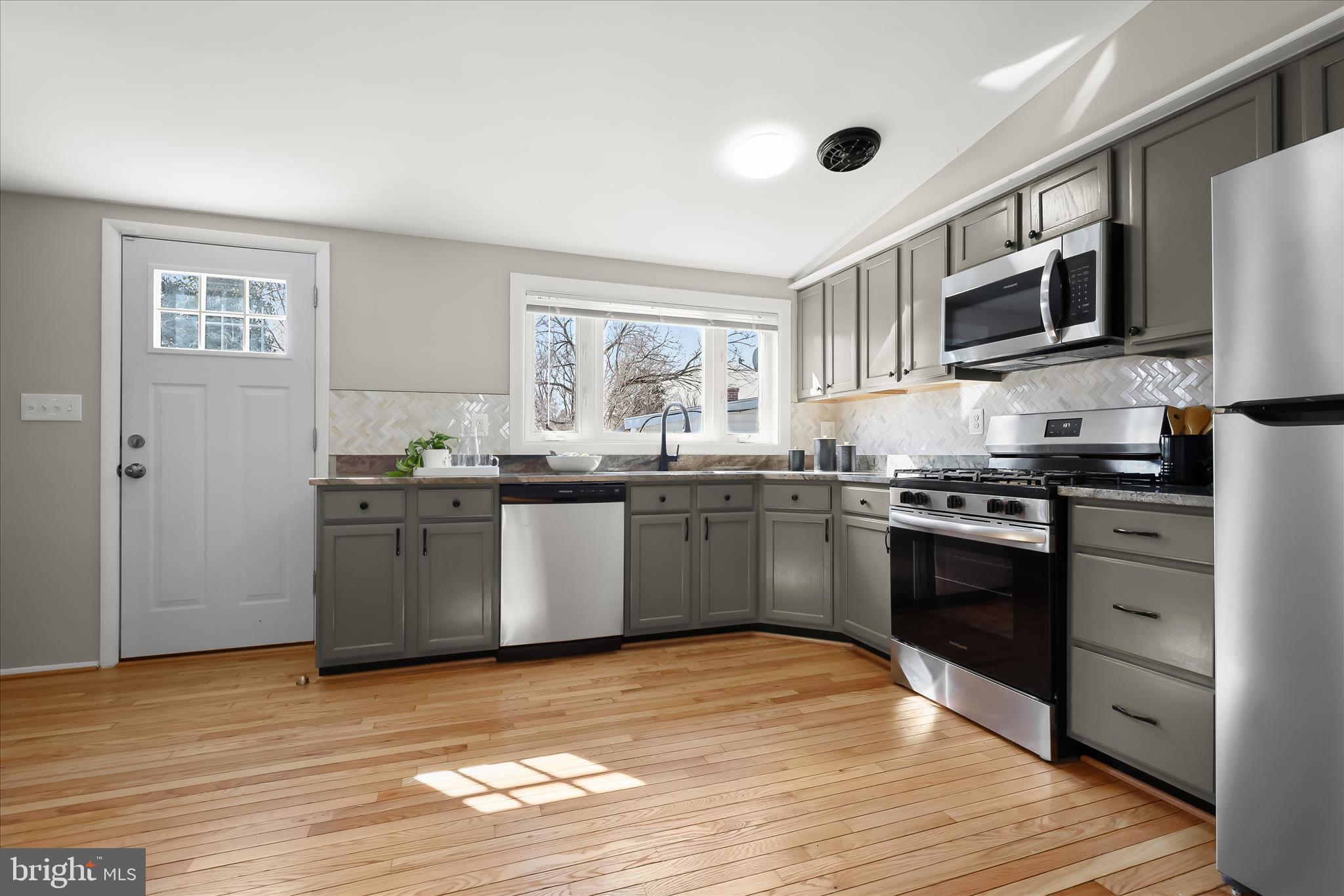 1009 Flagtree Lane Baltimore, MD 21208 - Photo 30 of 61 a kitchen with stainless steel appliances kitchen island granite countertop a sink cabinets and wooden floor