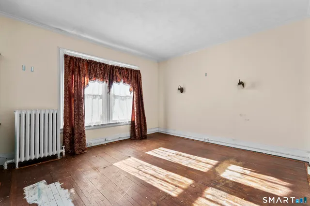 an empty room with wooden floor cabinet and windows