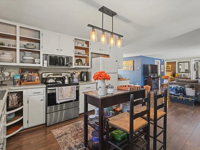 a kitchen with stainless steel appliances granite countertop a stove top oven a dining table and chairs with wooden floor