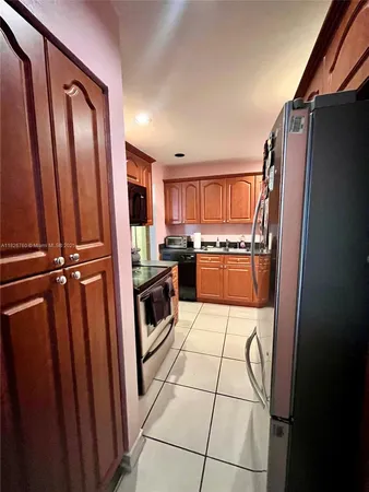 a kitchen with granite countertop a refrigerator and a stove top oven