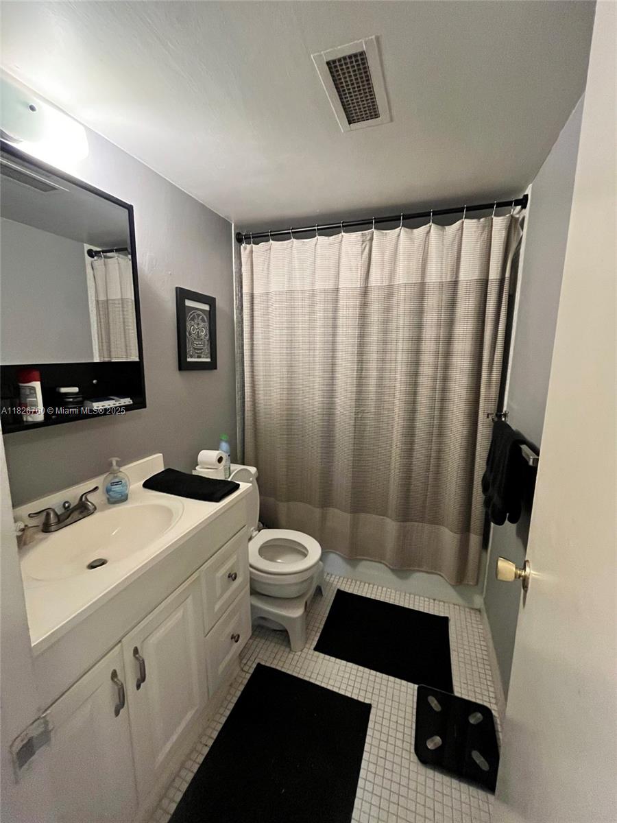 8325 Southwest 72nd Avenue, Unit 214C Miami, FL 33143 - Photo 9 of 12 a bathroom with a toilet a sink a vanity and mirror