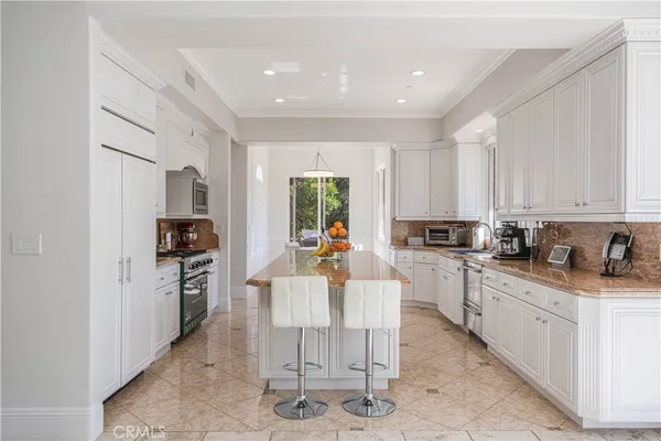 a view of a kitchen with kitchen island granite countertop lots of counter top space and stainless steel appliances
