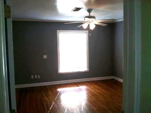 a view of empty room with wooden floor and fan