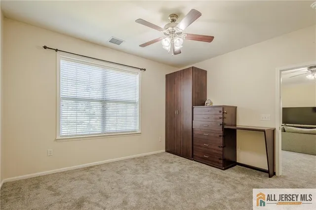 an empty room with chandelier fan and windows