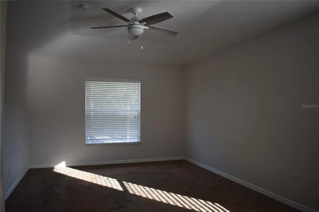 an empty room with a window and a fan