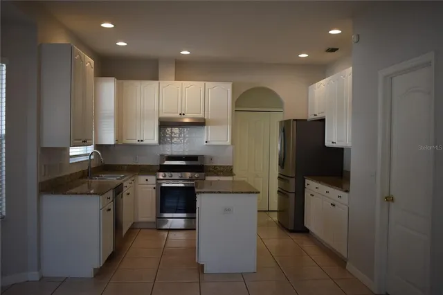 a kitchen with stainless steel appliances granite countertop a refrigerator a stove and a sink