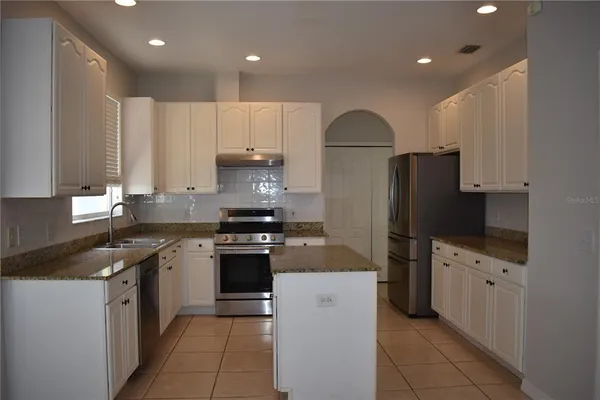 a kitchen with kitchen island granite countertop a stove sink and refrigerator