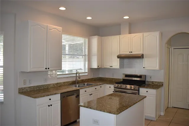 a kitchen with granite countertop a sink stove and cabinets