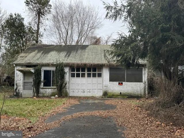 a view of a white house with a large tree next to a yard