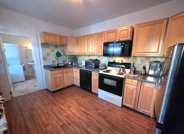 a kitchen with granite countertop a stove top oven a sink dishwasher and a refrigerator with wooden floor