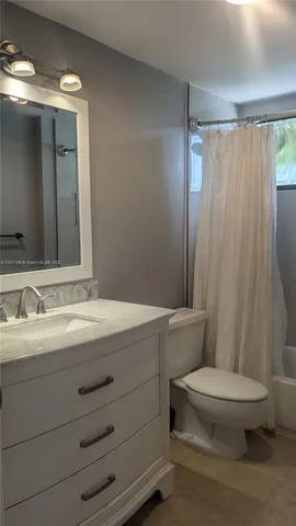 a bathroom with a sink a toilet a mirror and shower curtain