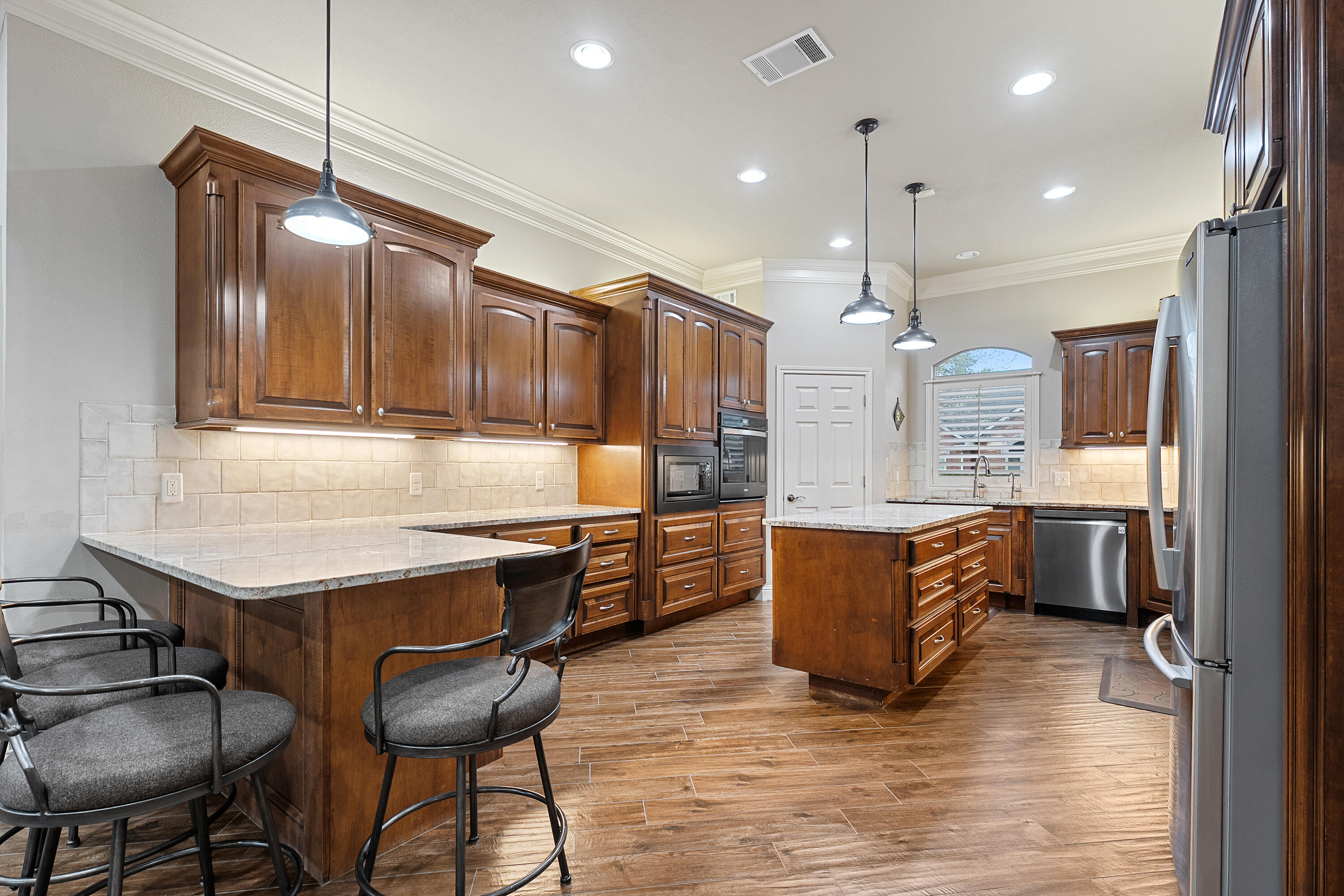 7502 Norfolk Avenue Lubbock, TX 79423 - Photo 11 of 41 a kitchen with kitchen island granite countertop wooden cabinets and refrigerator