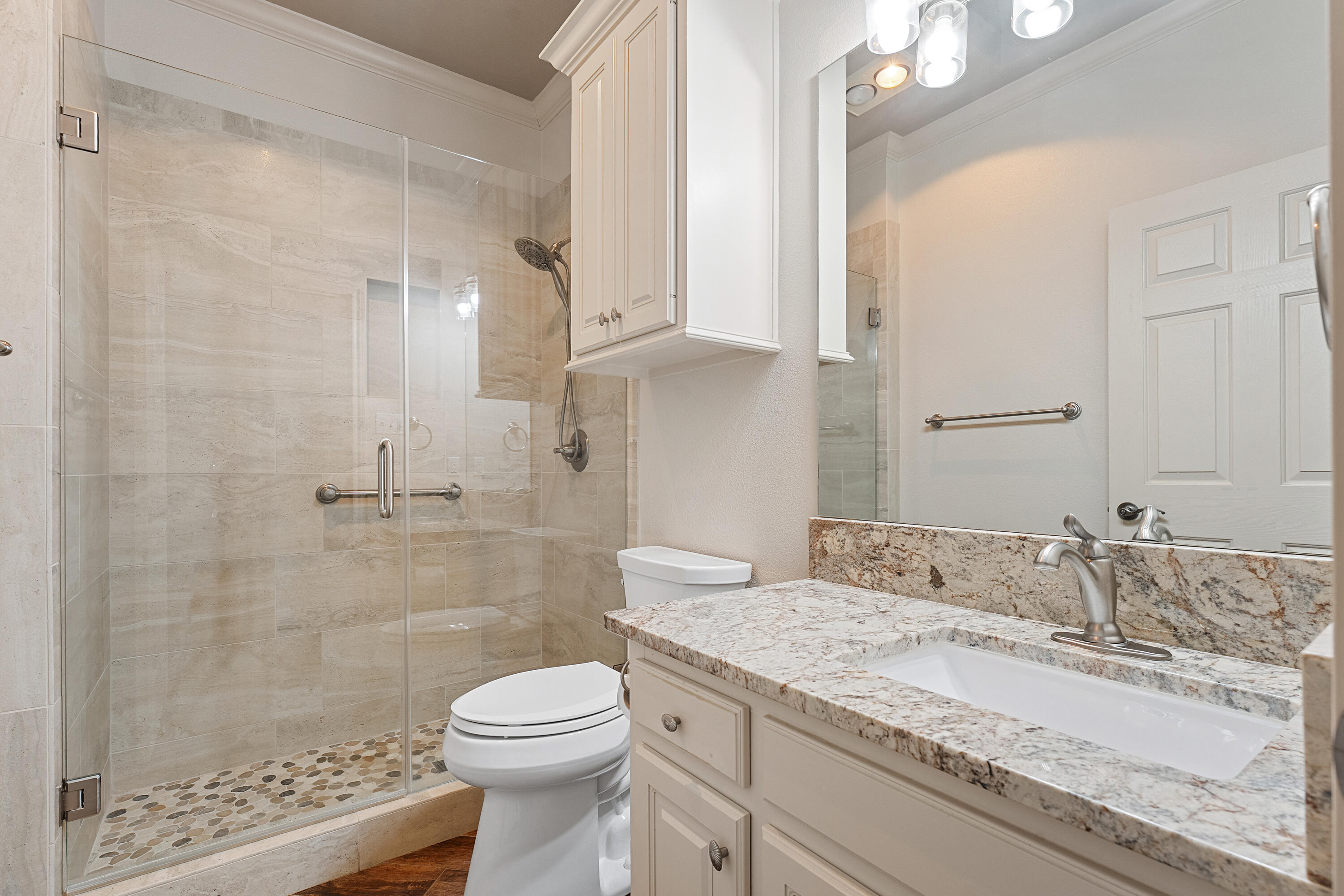7502 Norfolk Avenue Lubbock, TX 79423 - Photo 27 of 41 a bathroom with a granite countertop sink a toilet a mirror and shower