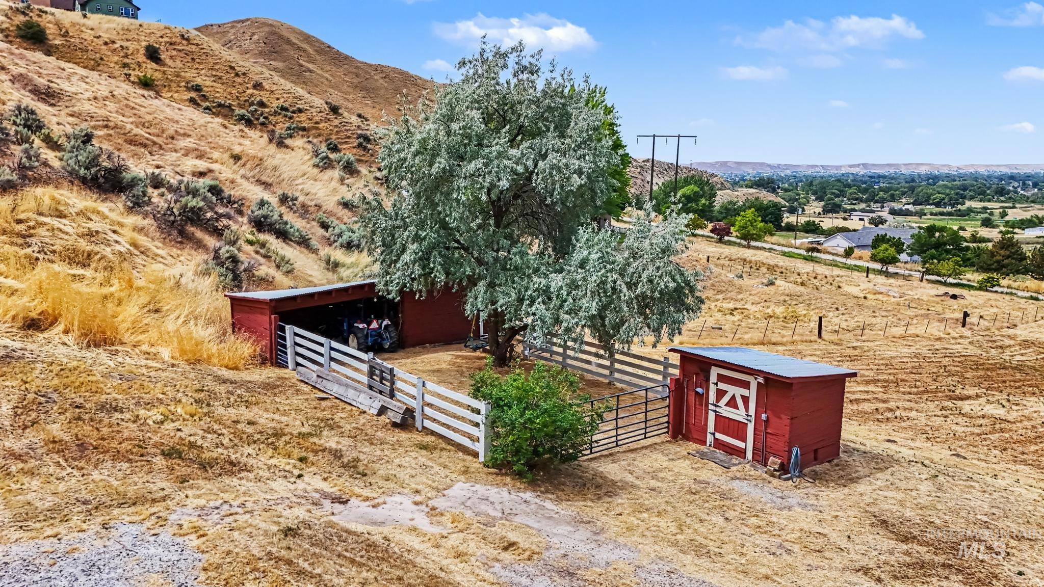 4311 Frozen Dog Road Emmett, ID 83617 - Photo 6 of 31 Agricultural outbuildings featuring a red open-sided shed with white fencing and an additional red storage shed