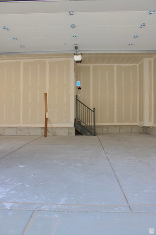 2613 Scarlet Road, Unit 258 Eagle Mountain, UT 84005 - Photo 30 of 32 Spacious garage with concrete flooring, unfinished drywall, and an integrated staircase featuring a black metal railing