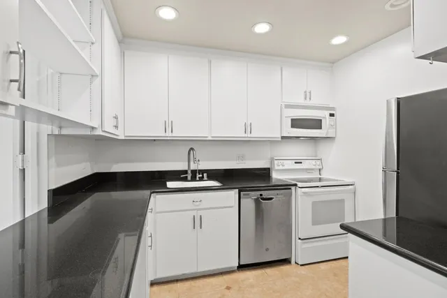 a kitchen with stainless steel appliances granite countertop a sink a stove a refrigerator and cabinets