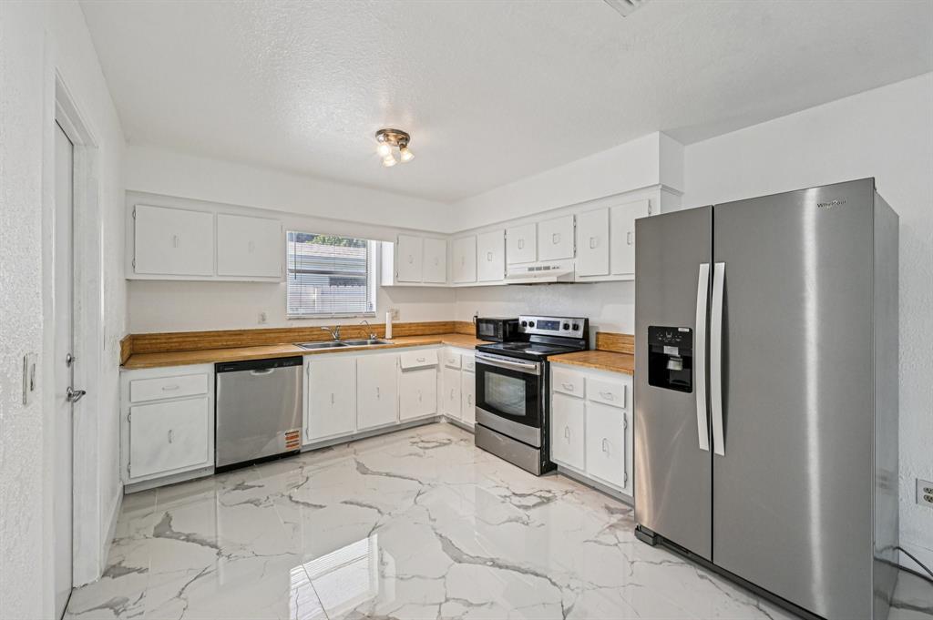 4549 Baldric Street Boca Raton, FL 33428 - Photo 30 of 43 a kitchen with granite countertop a refrigerator and a stove top oven