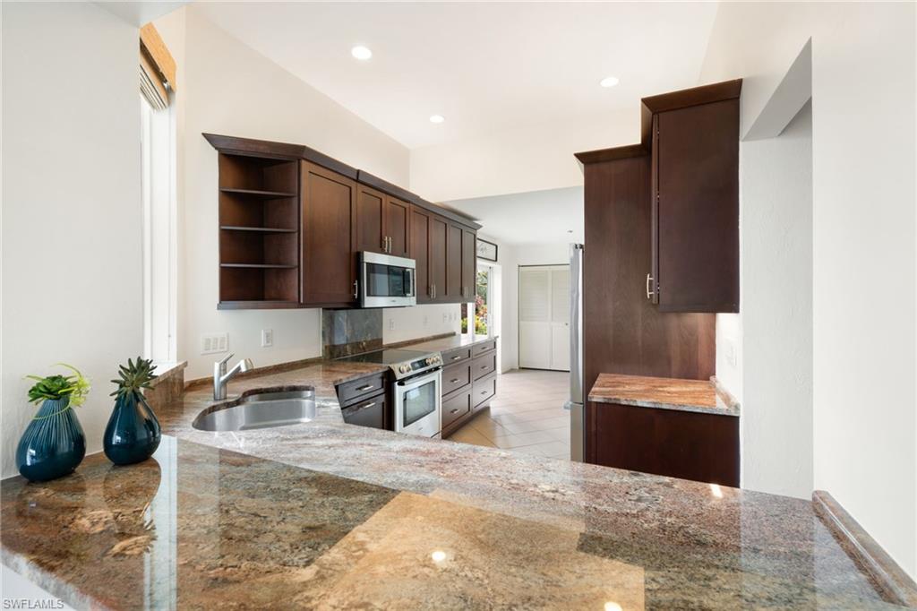 2153 Paget Circle Naples, FL 34112 - Photo 27 of 49 Kitchen with open shelves, dark brown cabinetry, stainless steel appliances, dark stone countertops, and recessed lighting