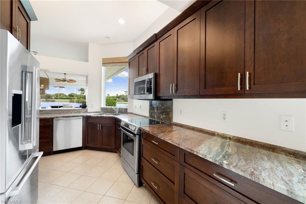 2153 Paget Circle Naples, FL 34112 - Photo 28 of 49 Kitchen with stainless steel appliances, dark stone counters, dark brown cabinets, light tile patterned flooring, and ceiling fan