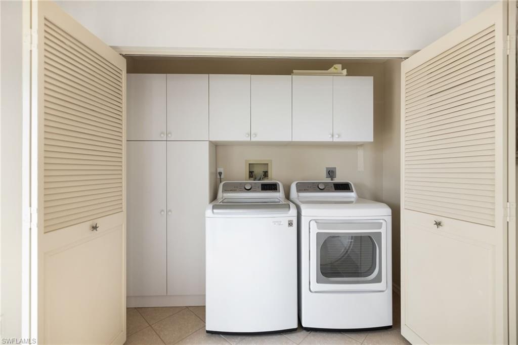 2153 Paget Circle Naples, FL 34112 - Photo 32 of 49 Laundry area with cabinet space, washing machine and dryer, and light tile patterned flooring