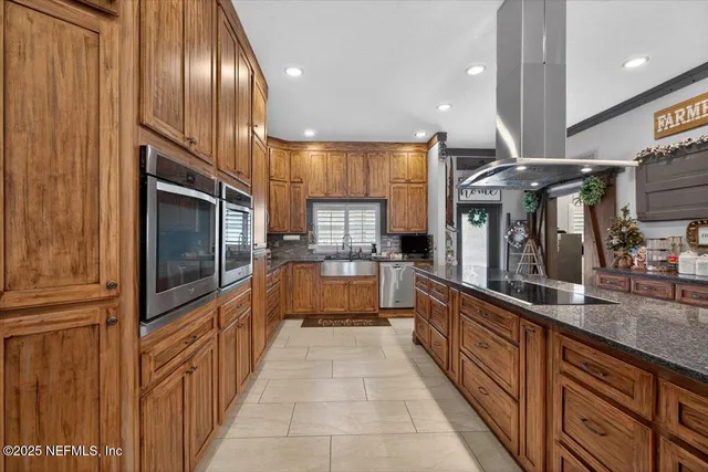 a kitchen with stainless steel appliances granite countertop a sink a stove and a wooden cabinets