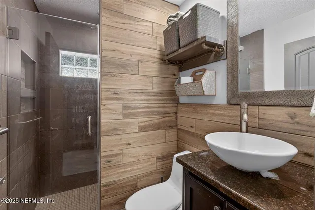 a bathroom with a granite countertop sink and a toilet