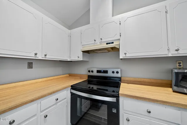 a kitchen with stainless steel appliances granite countertop white cabinets and a stove