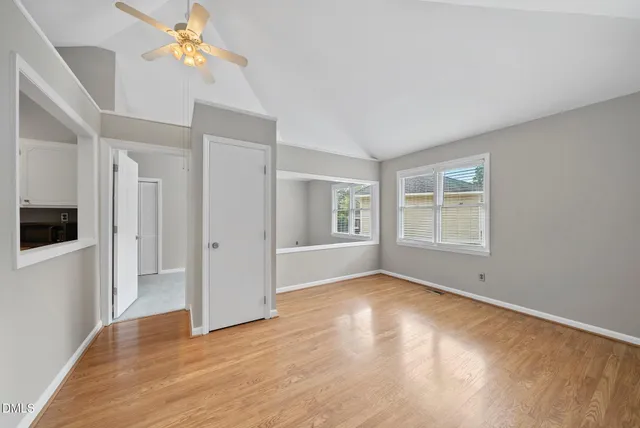 a view of empty room with wooden floor and fan