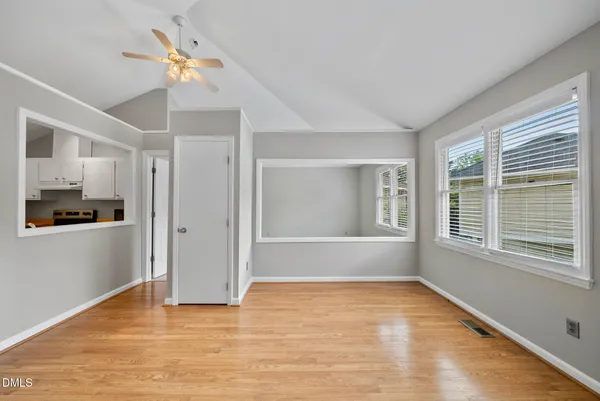 a view of an empty room with a window and wooden floor