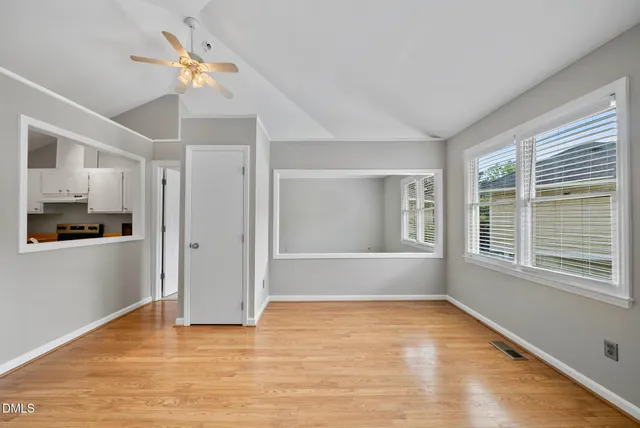 a view of an empty room with a window and wooden floor