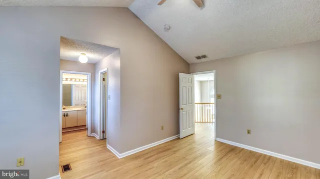 a view of an empty room with wooden floor and closet