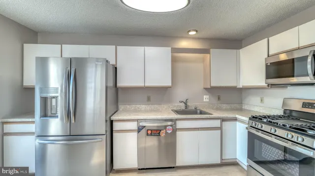 a kitchen with stainless steel appliances granite countertop a refrigerator a stove a sink and a microwave