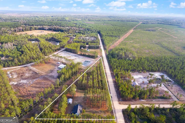 a view of a house with a yard and large trees