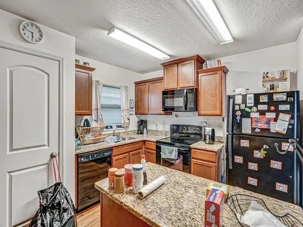 a kitchen with stainless steel appliances granite countertop a stove top oven a sink a dining table and chairs with wooden floor