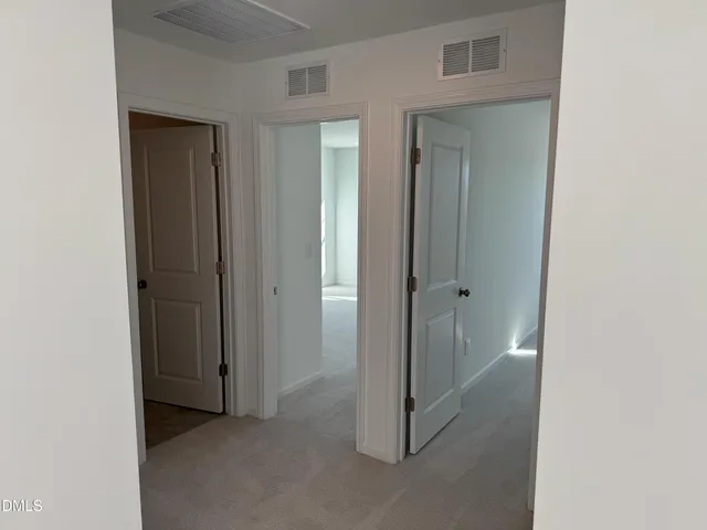 a view of an empty room with closet and a bathroom