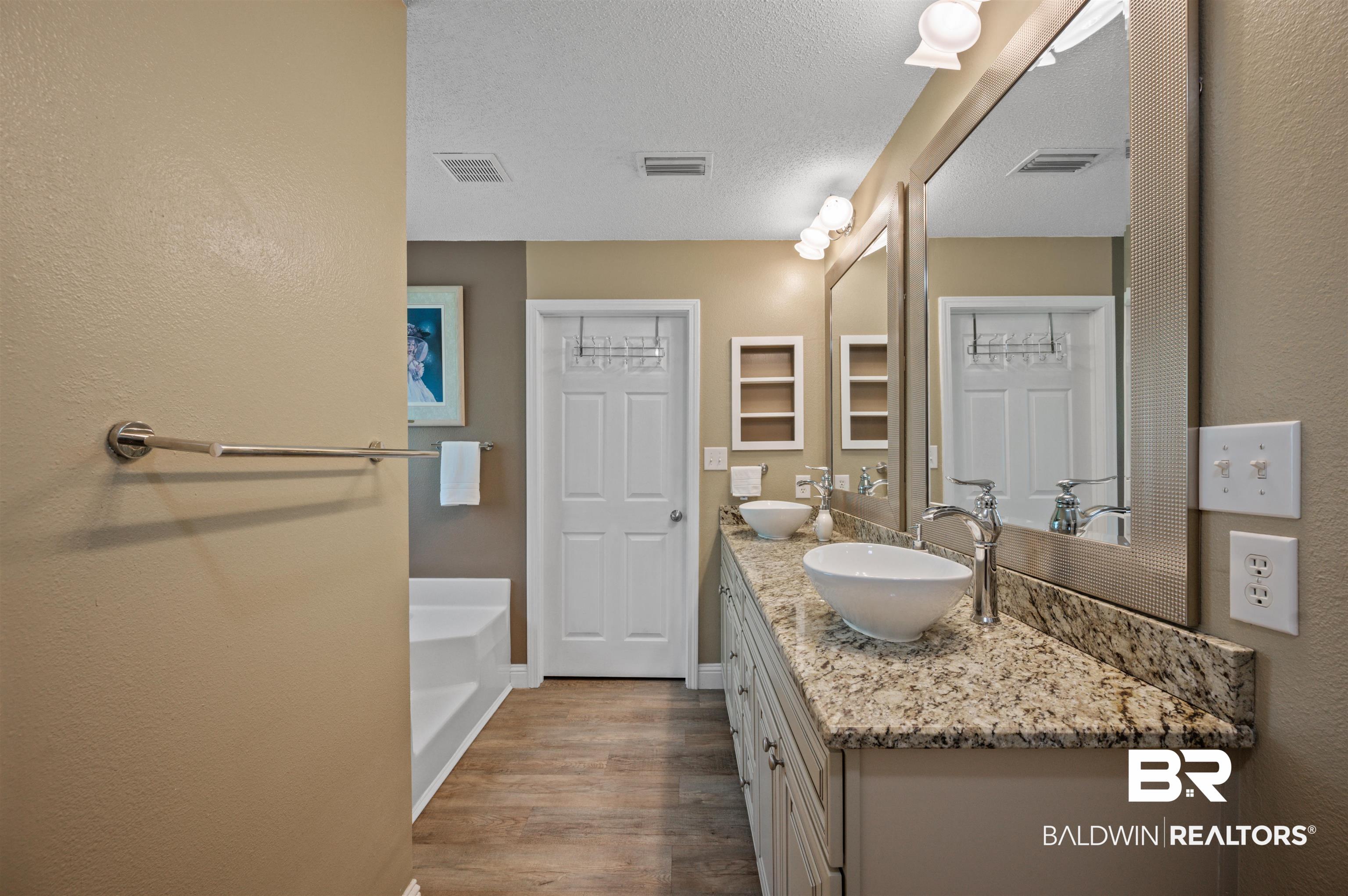 11705 Venice Boulevard Foley, AL 36535 - Photo 26 of 43 Bathroom with hardwood / wood-style floors, vanity, and a bathtub