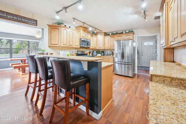 a kitchen with stainless steel appliances a dining table chairs and wooden floor