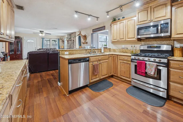 a kitchen with stainless steel appliances granite countertop a stove and a wooden floors