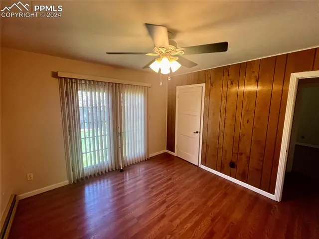 an empty room with wooden floor fan and windows