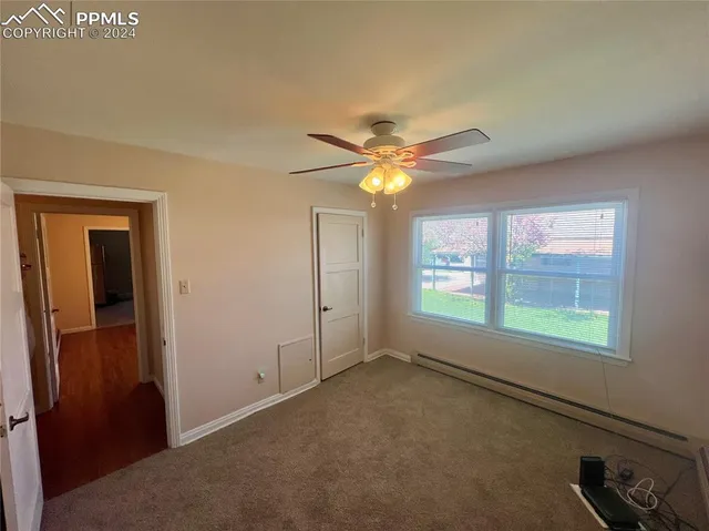 an empty room with windows and fan